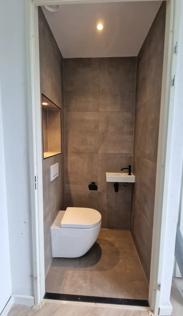 QA Renovatie: toilet met grijze tegels en fonteintje